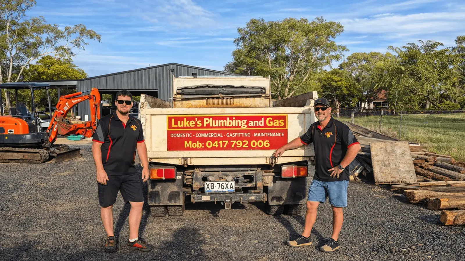 Luke's Plumbing & Gas signed tipper truck and excavator on a sunlit Toowoomba job site